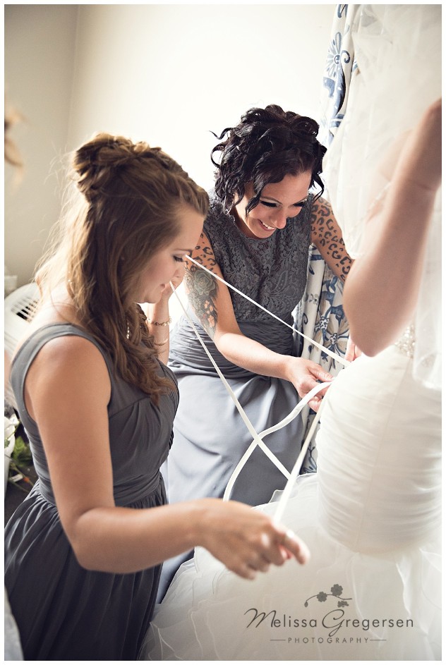 Bridesmaids helping with the wedding dress at Bay Pointe Inn on Gun Lake photographed by Melissa Gregersen Photography