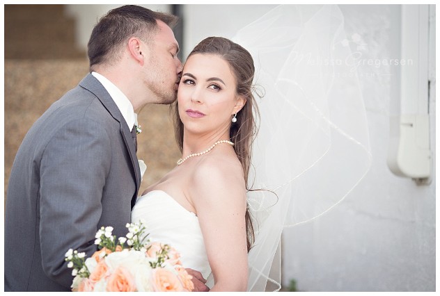 Veil blowing in the wind while groom steals a kiss 