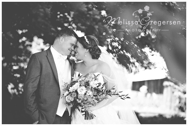 Black and white photograph of scrunchy nose smiles with bride and groom