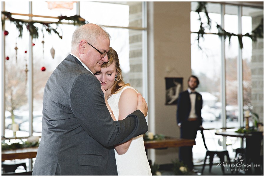 Father daughter dance at wedding with groom watching in the distance.